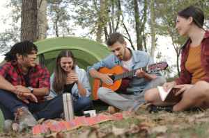 acoustic guitar played by a man sitting on grass field